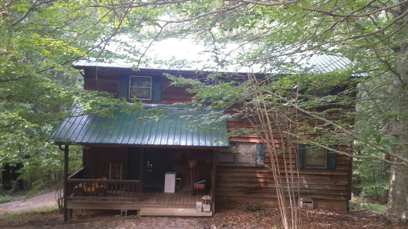 Green metal roof and covered porch on a log cabin in Garland