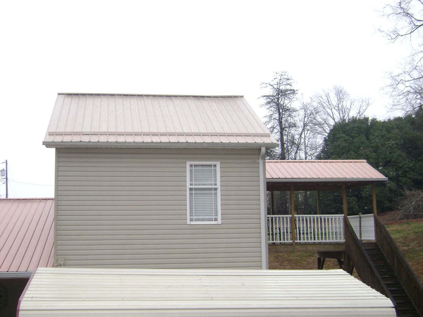 Tan metal roofs on a two story addition and attached porch, from a Roof Replacement job in Garland