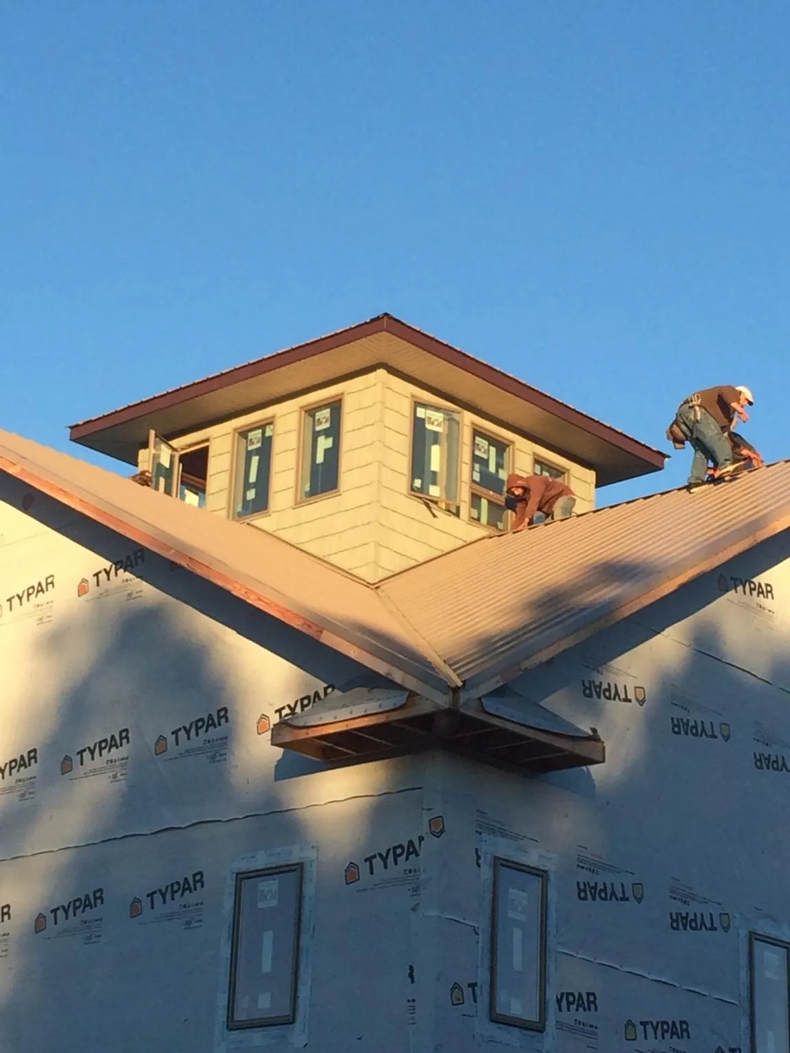 Roofers working around a rooftop cupola on a new metal roof at sunset — Roof Waterproofing in Garland by Roofing Brothers